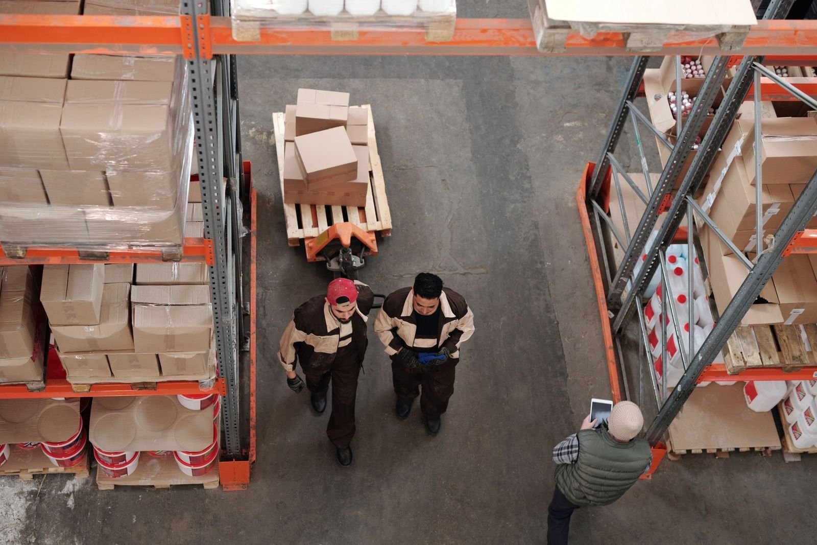 Trabajadores preparando envíos con cajas y tarimas en un almacén