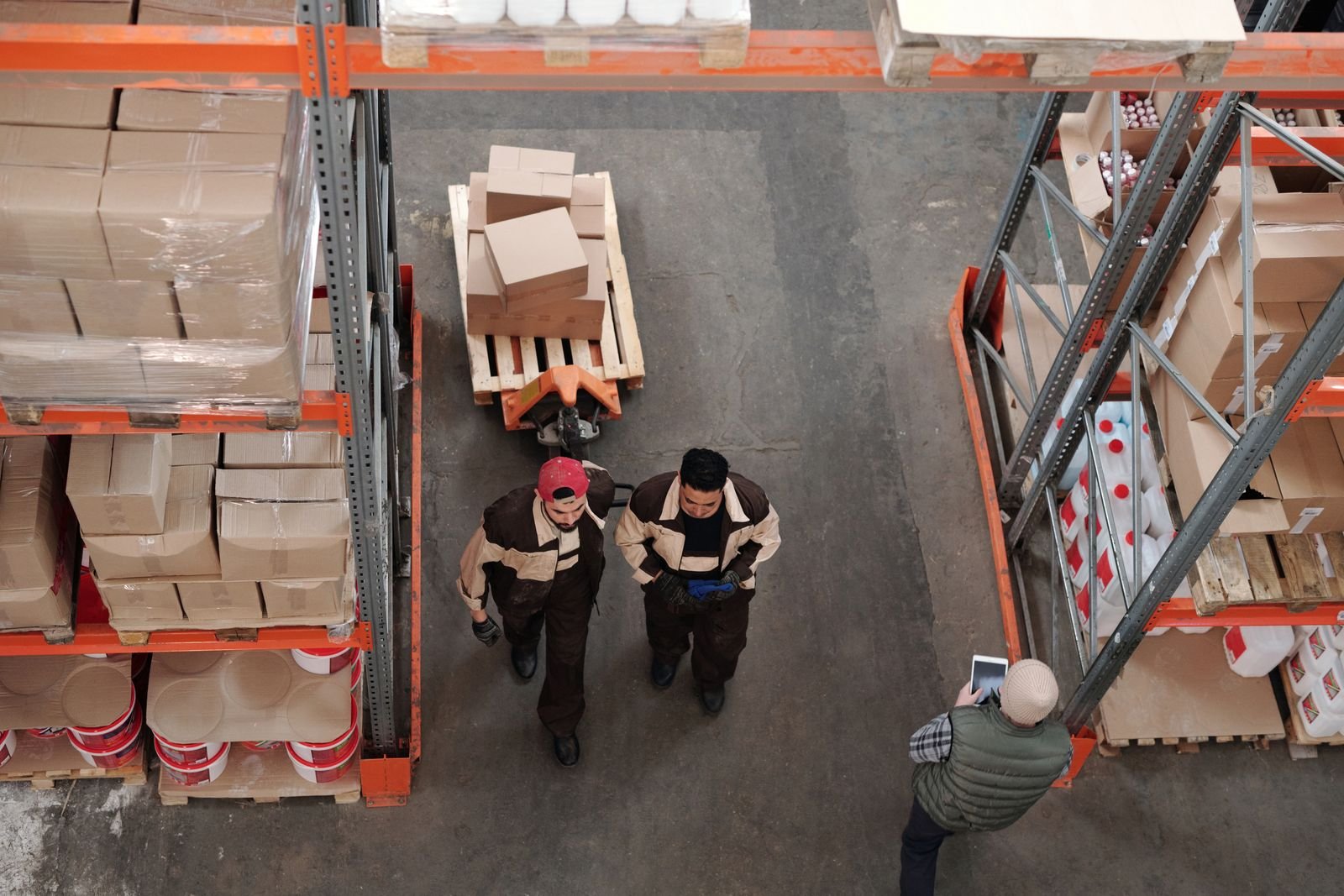 Trabajadores preparando envíos con cajas y tarimas en un almacén