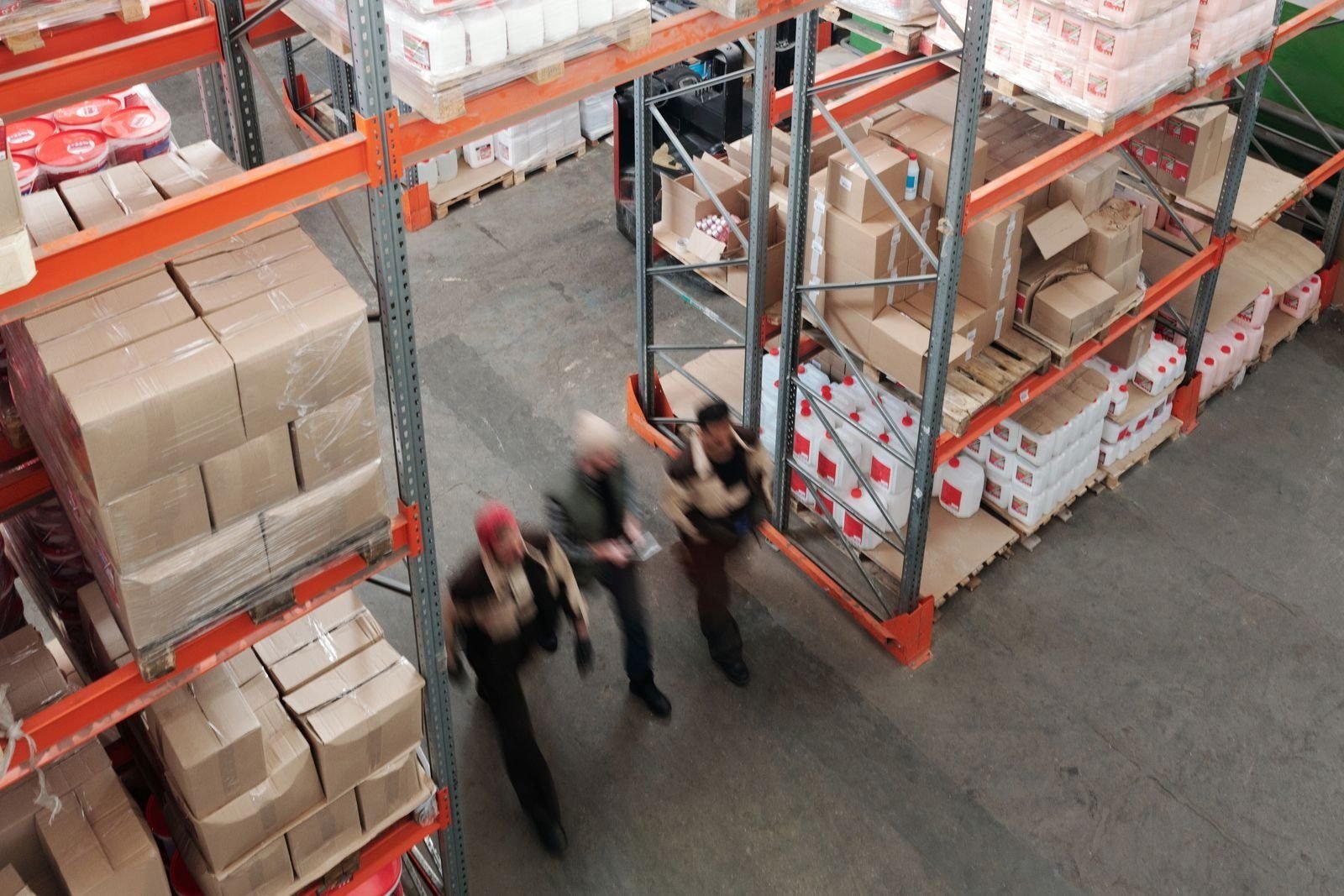 Trabajadores en movimiento entre estanterías llenas de un almacén