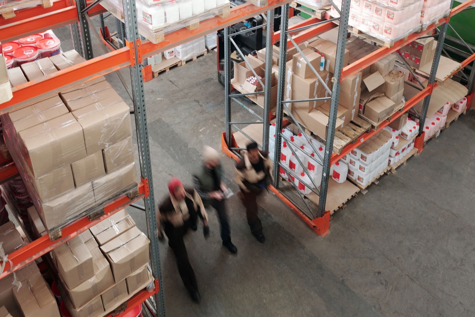 Trabajadores en movimiento entre estanterías llenas de un almacén