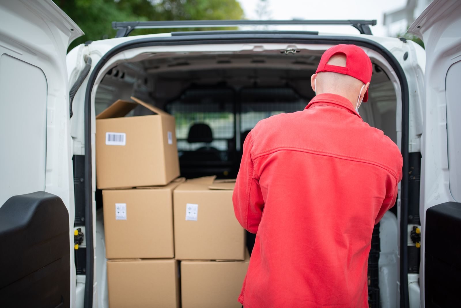 Repartidor cargando cajas en la parte trasera de una furgoneta blanca