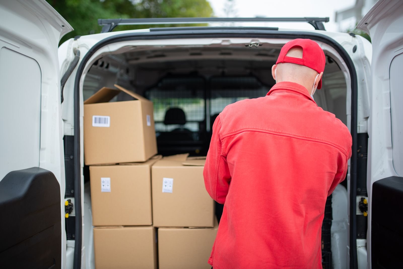 Repartidor cargando cajas en la parte trasera de una furgoneta blanca